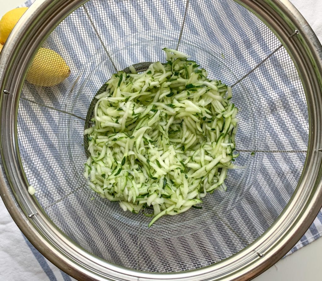 Shredded zucchini draining in a colander