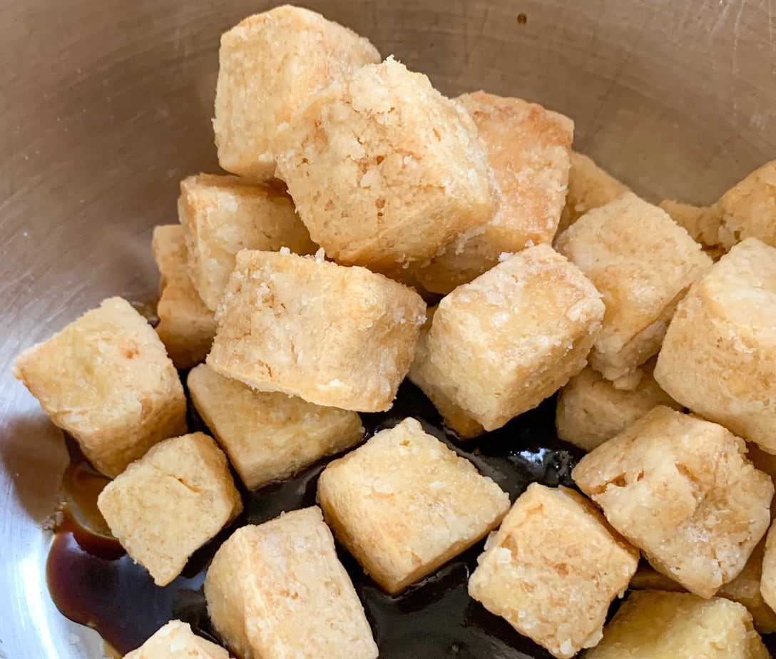 Fried tofu cubes, sitting in a bowl with hoisin sauce.