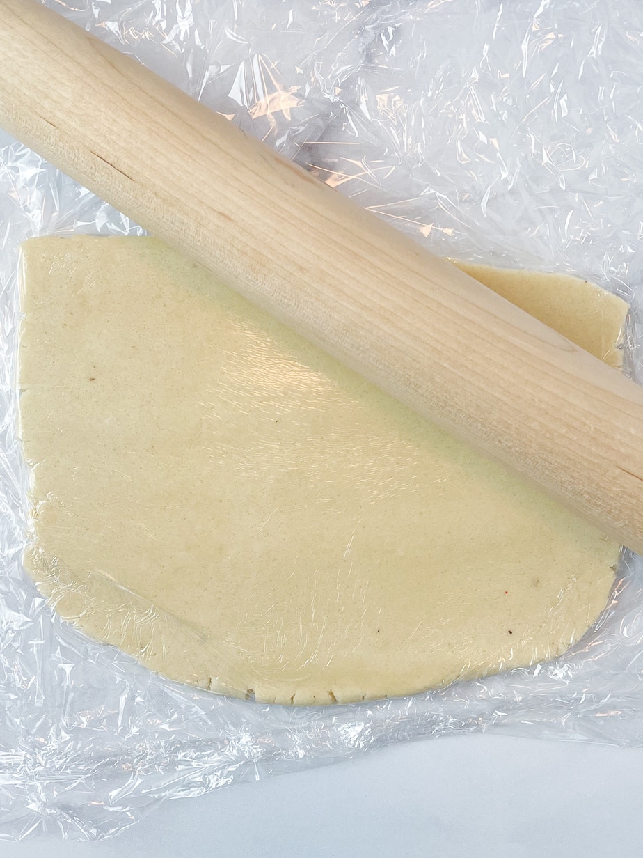 Rolling the cookie dough out between two pieces of plastic with a rolling pin