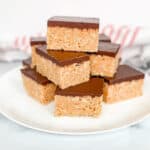 A plate stacked with peanut butter and chocolate Rice Krispies Treats. A red striped towel in the background.