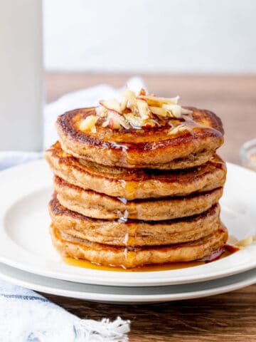 A stack of applesauce pancakes with syrup running off the side