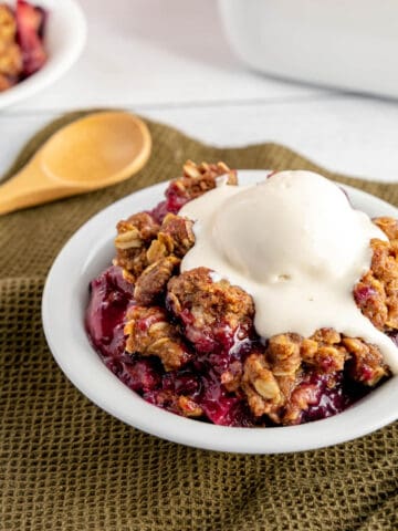 Apple blueberry crisp in a white bowl, placed on a green napkin.
