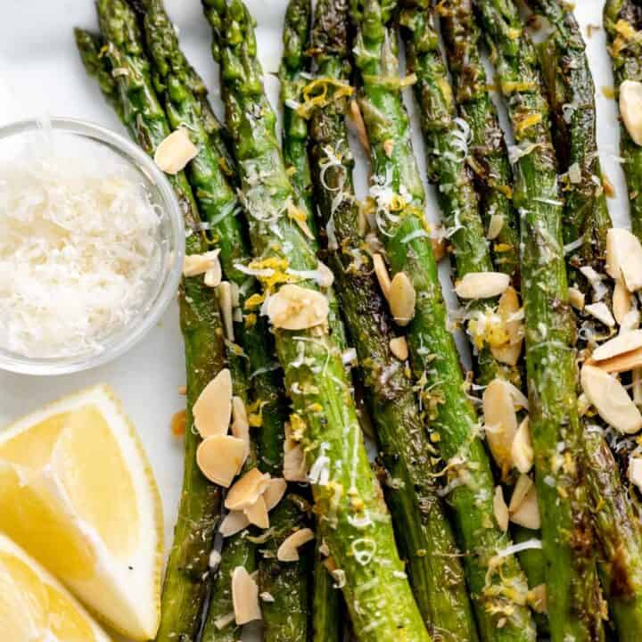 Asparagus on a platter with lemon and parmesan cheese and toasted almonds