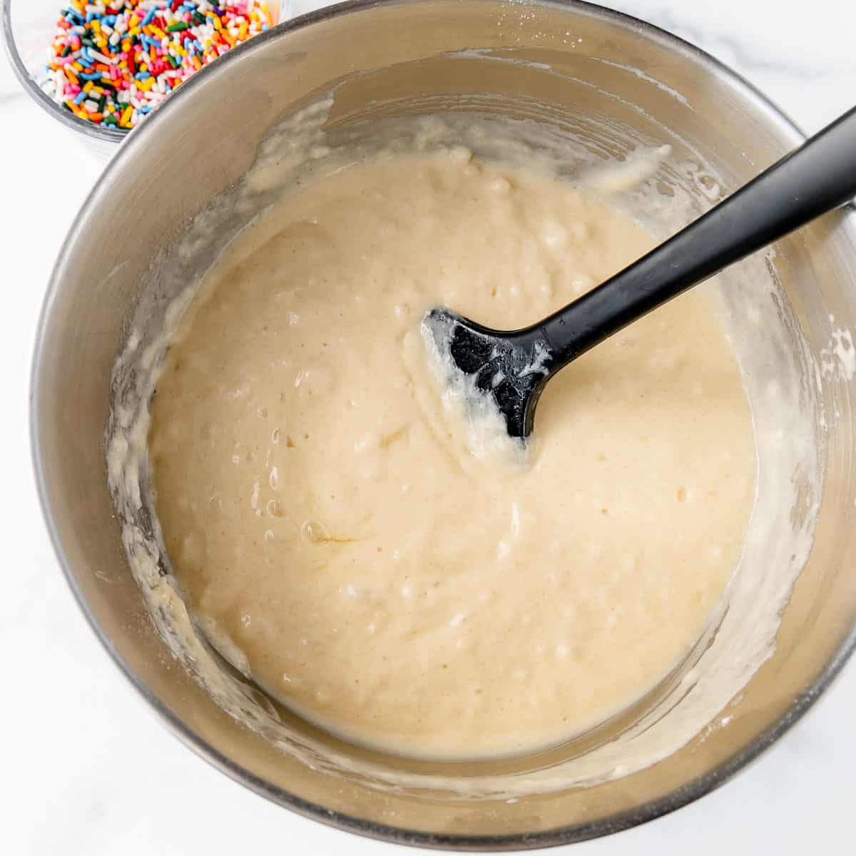 The mixed batter in a silver bowl with a black spatula.