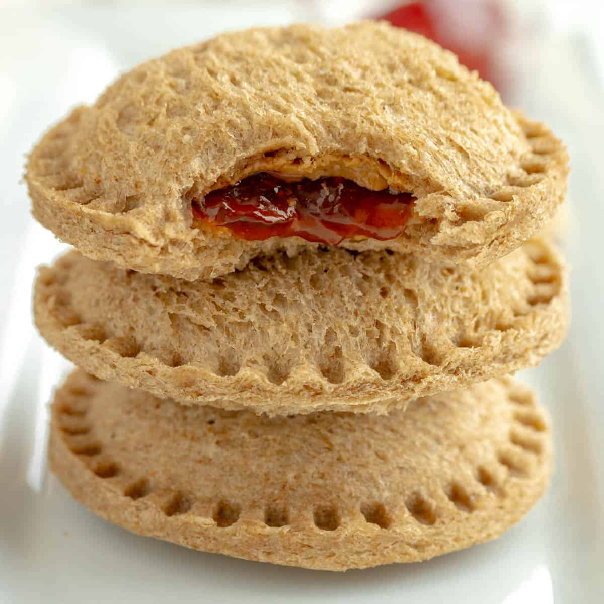Three Uncrustables stacked with jam filling oozing out.