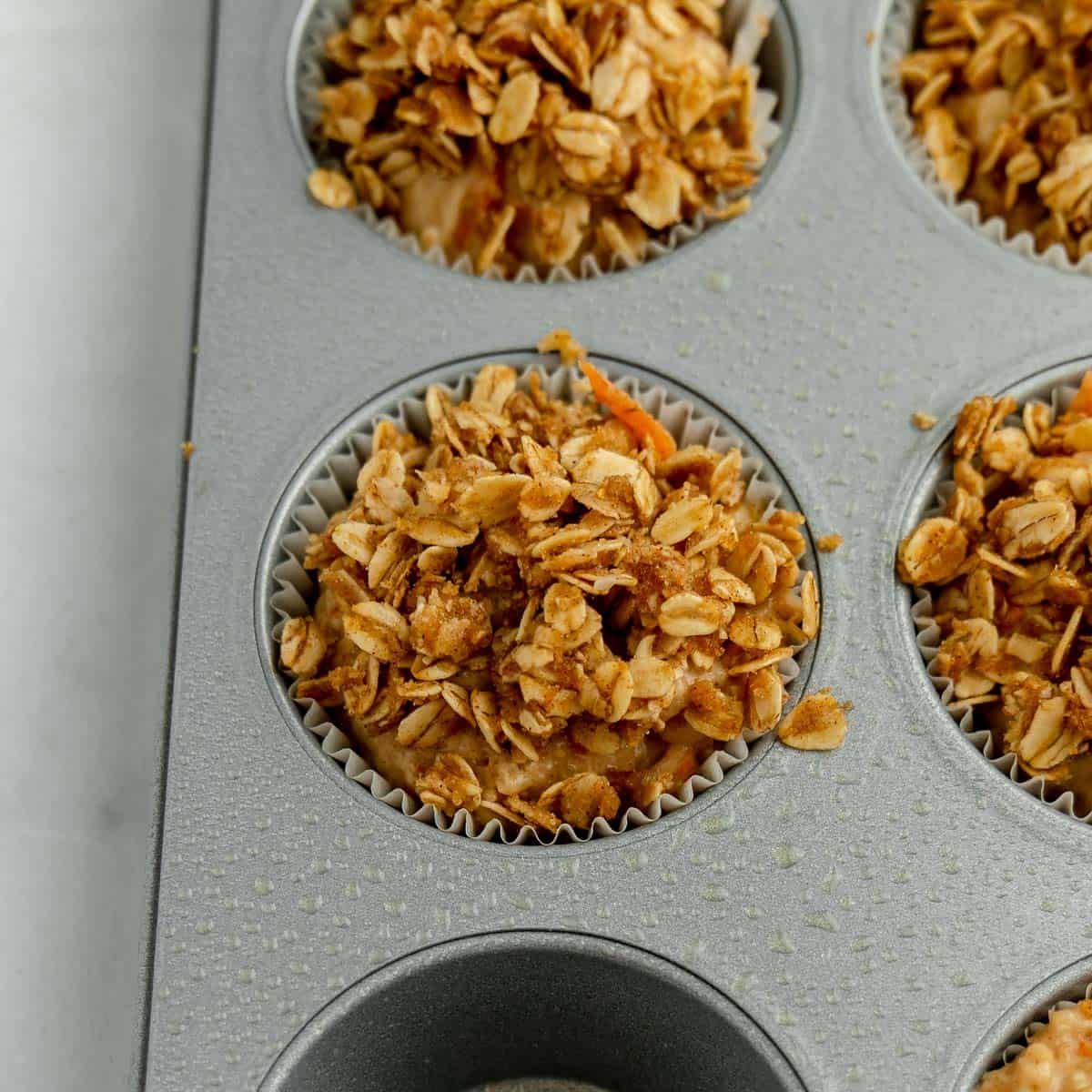 Muffins in a pan with oat topping.