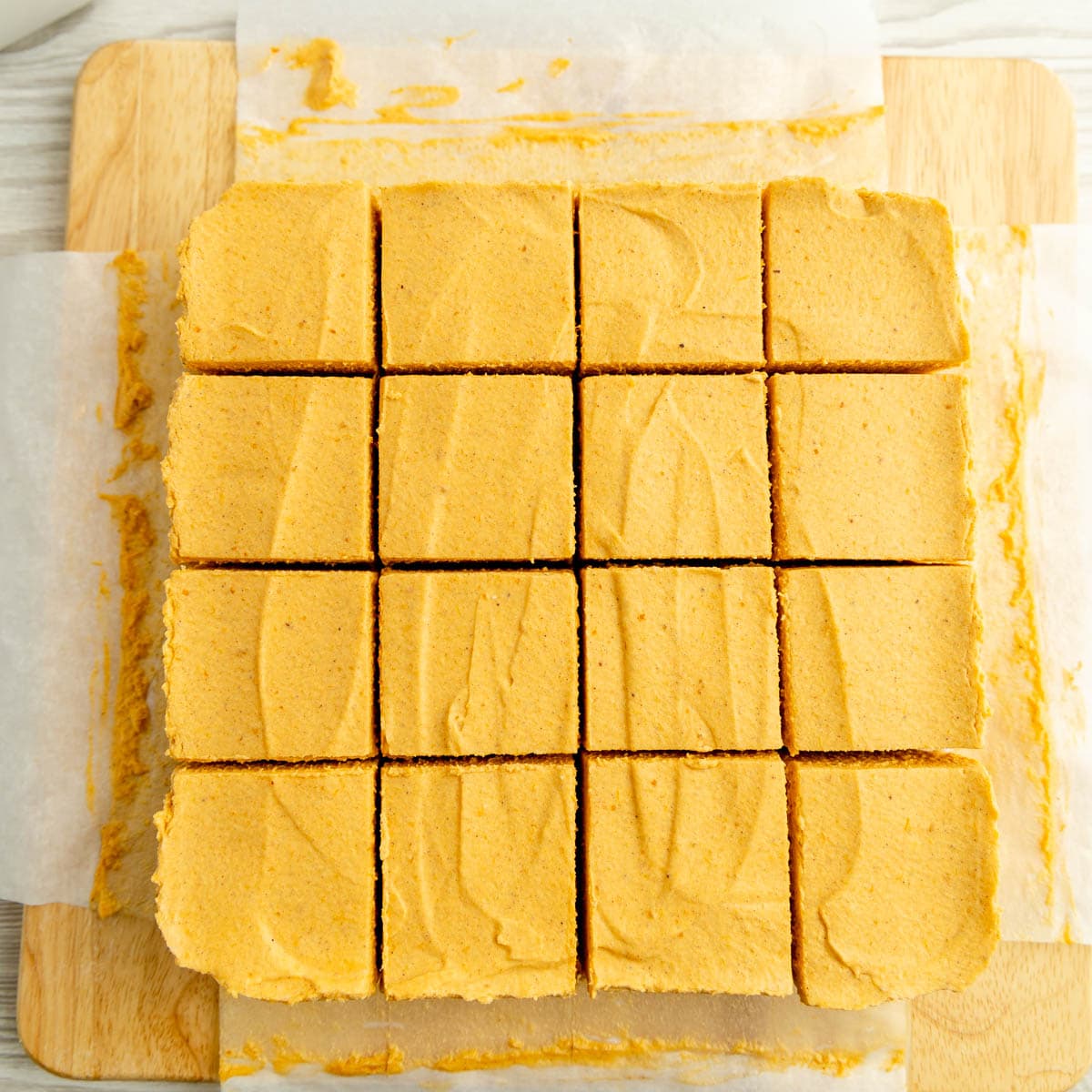 Pumpkin cheesecake bars cut into 16 squares.