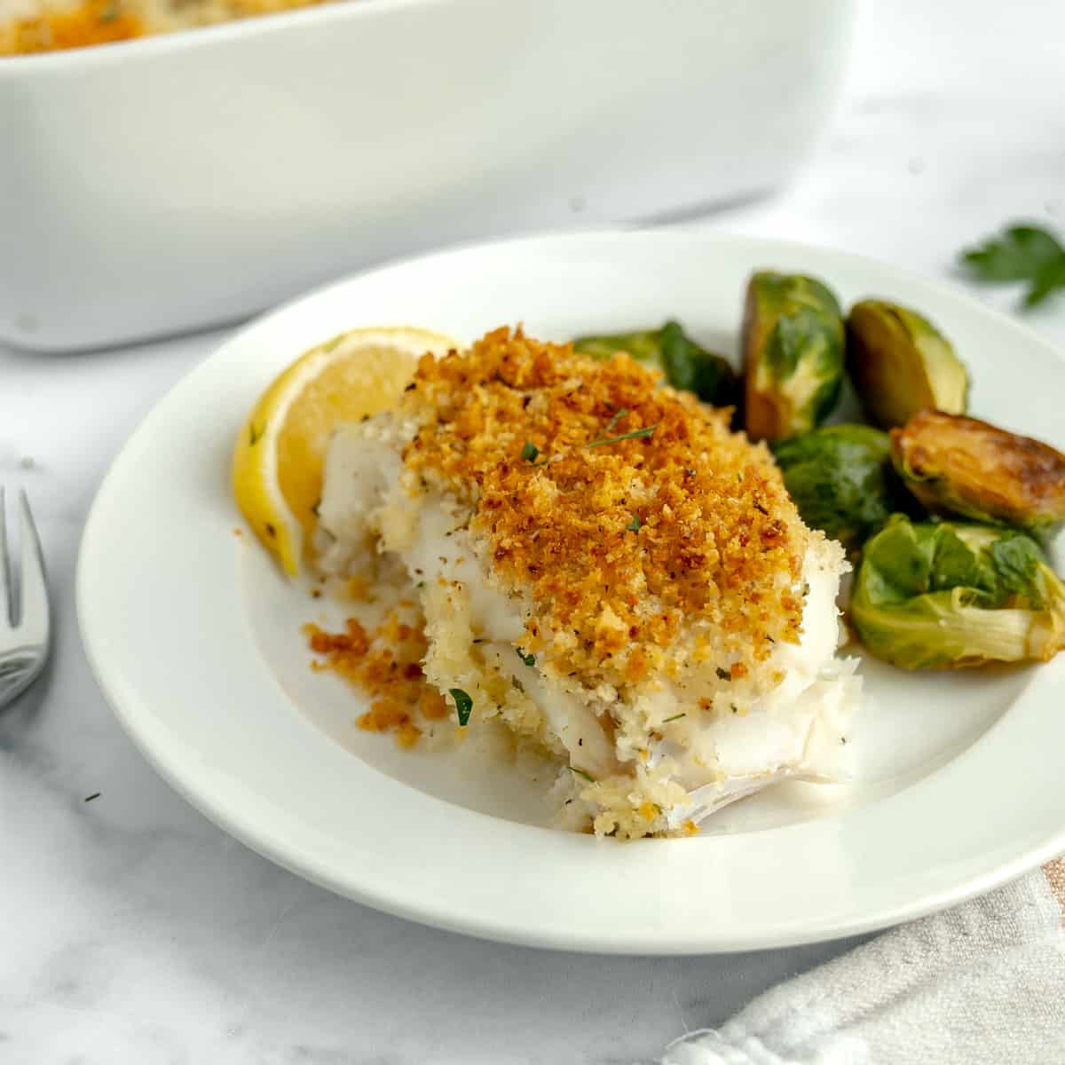 Baked fish on a plate with brussels sprouts.