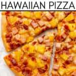 A close-up of a Hawaiian Pizza topped with ham, pineapple, and cheese, sliced and ready to serve. Text above reads "Easy Homemade Hawaiian Pizza.