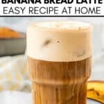 Iced Banana Bread Latte in a clear glass with a frothy top; blurred background highlighting a banana and baked goods. Text overlay reads “Banana Bread Latte Easy Recipe at Home.” Perfect for cozy coffee moments.
