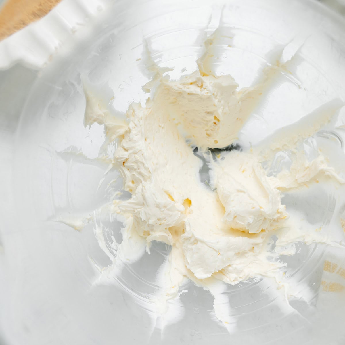 A glass mixing bowl with remnants of whipped cream cheese spread around the sides.