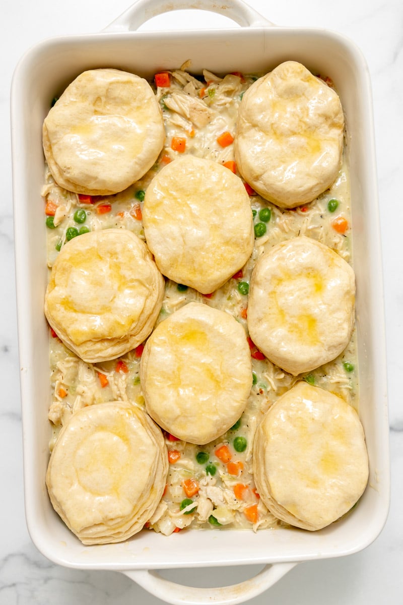 Chicken pot pie in a rectangular baking dish topped with eight biscuits.