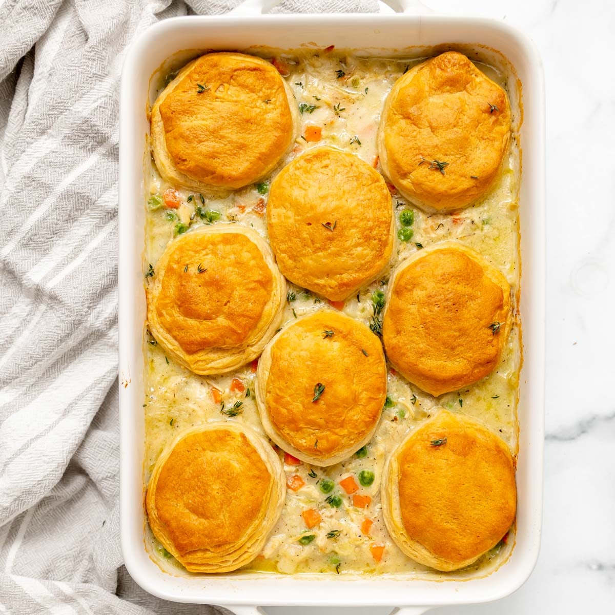A rectangular casserole dish filled with chicken pot pie topped with eight baked biscuits.