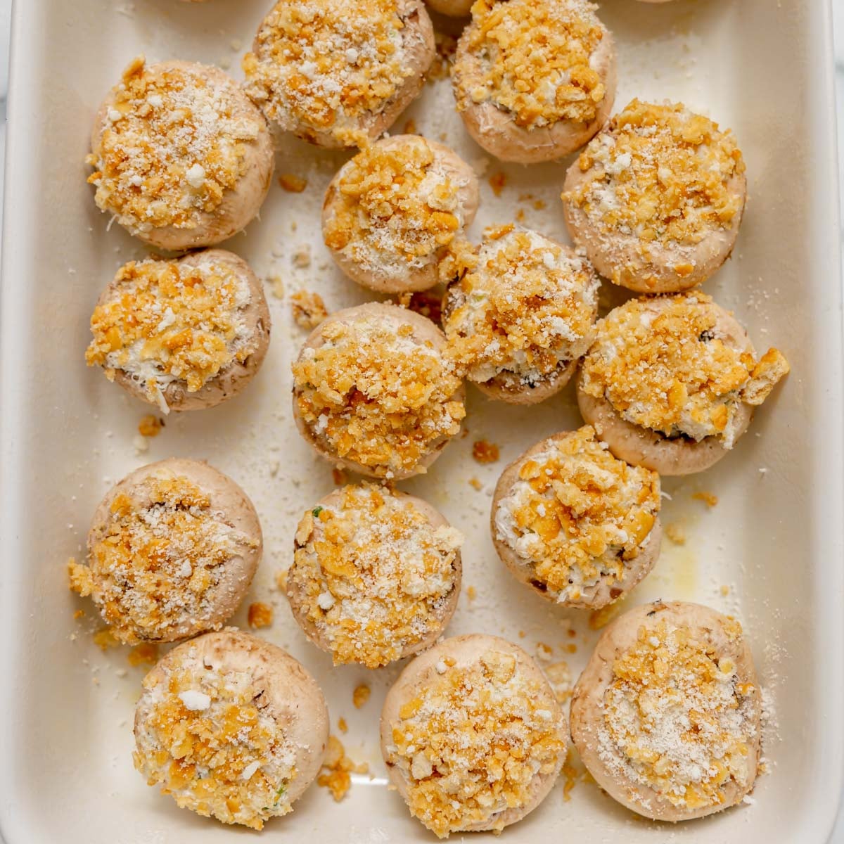 Stuffed mushrooms topped with breadcrumbs in a baking dish.